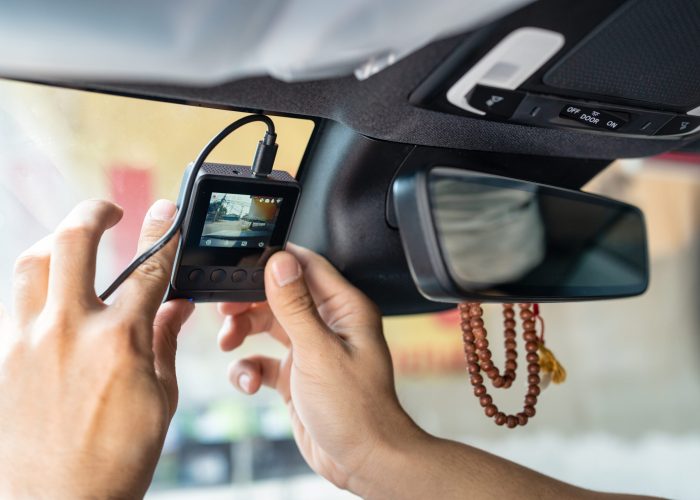 Hand of technician installing front camera car recorder on windscreen car